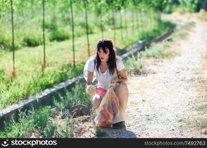 Young woman hand collecting garbage of the grass in the countryside. Woman hand collecting garbage of the grass in the countryside