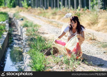 Young woman hand collecting garbage of the grass in the countryside. Woman hand collecting garbage of the grass in the countryside