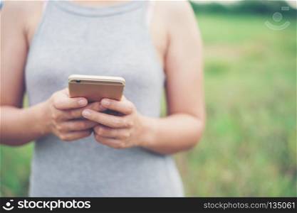 Young woman hands typing smartphone in the park.