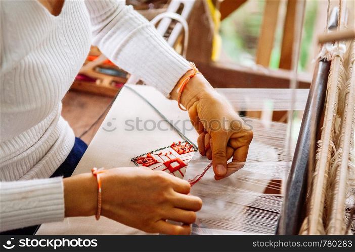 Young woman hands working on Vintage wooden weaving loom with silk fiber, handicraft work, weaving tool. Culture tourism concept