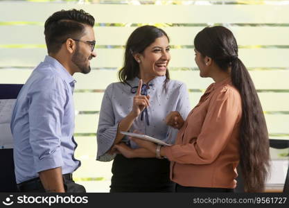 YOUNG WOMAN HAPPILY TALKING TO HER COLLEAGUES IN OFFICE