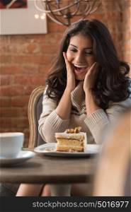 Young woman happy with her cake in a cafe indoors. Shallow depth of field.