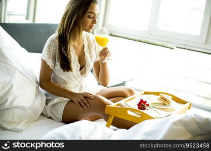 Young woman having breakfast in bed in the bedroom