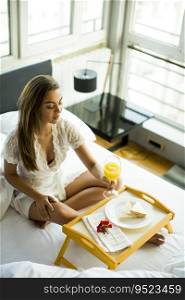Young woman having breakfast in bed in the bedroom