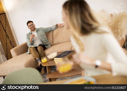 Young woman having breakfast in the kitchen with a boyfriend sitting in the background