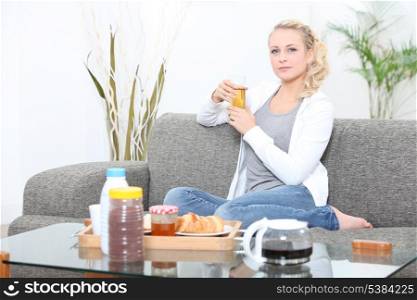 Young woman having breakfast on a sofa