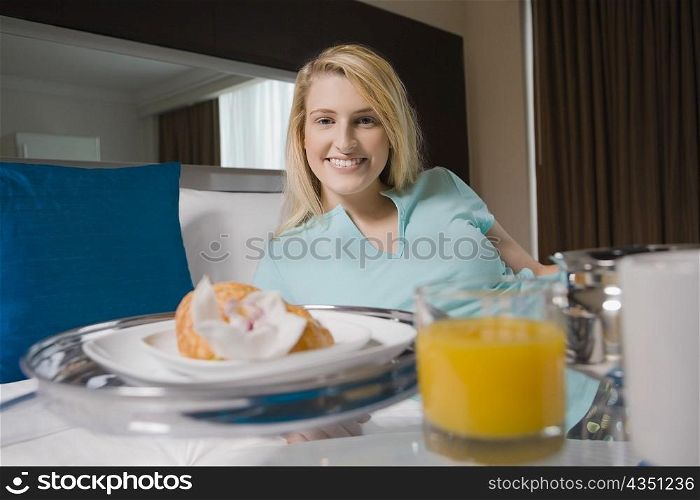 Young woman having breakfast on the bed