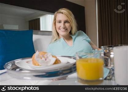 Young woman having breakfast on the bed