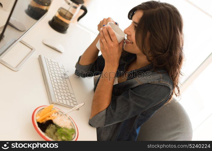 Young woman having breakfast on the computer desk