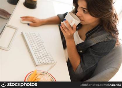 Young woman having breakfast on the computer desk