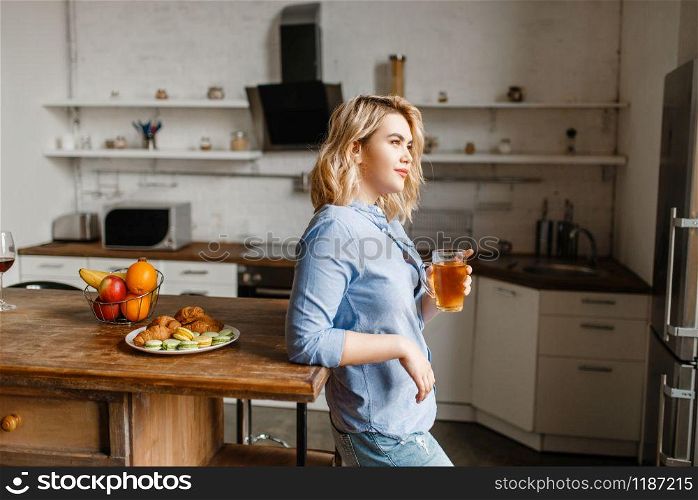Young woman having breakfast with croissants and cookies. Female person eats dessert on the kitchen, good morning, happy lifestyle