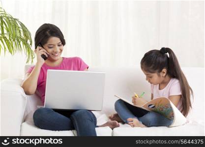 Young woman having conversation on mobile phone while girl drawing