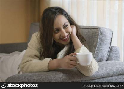Young woman having cup of coffee on sofa