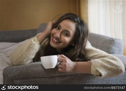Young woman having cup of coffee on sofa