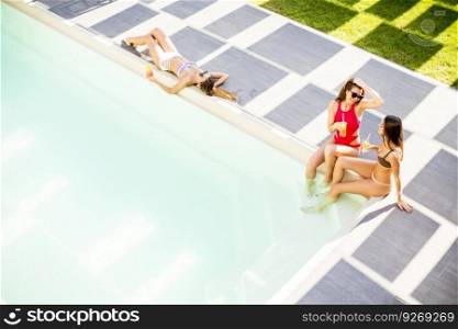 Young woman having fun and drinking coctail by the pool at hot summer day, View from above