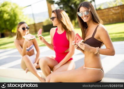 Young woman having fun and eating watermelon by the pool at hot summer day