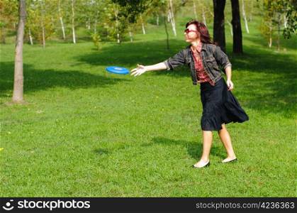 Young woman having fun with frisbee in the parkin sunny summer day.