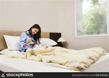 Young woman having her morning tea in bed
