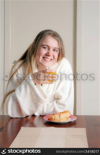 young woman having juice and crossiant for breakfast