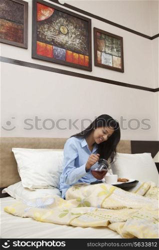 Young woman having morning tea in bed
