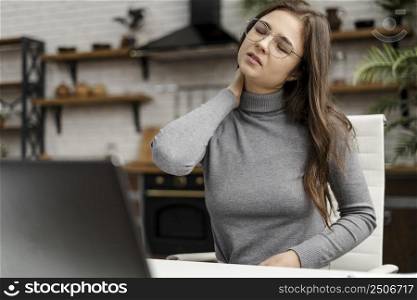 young woman having neckache while working from home