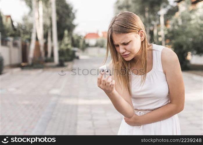 young woman having stomach ache holding white pills bottle