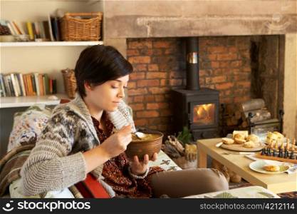 Young woman having tea by fire