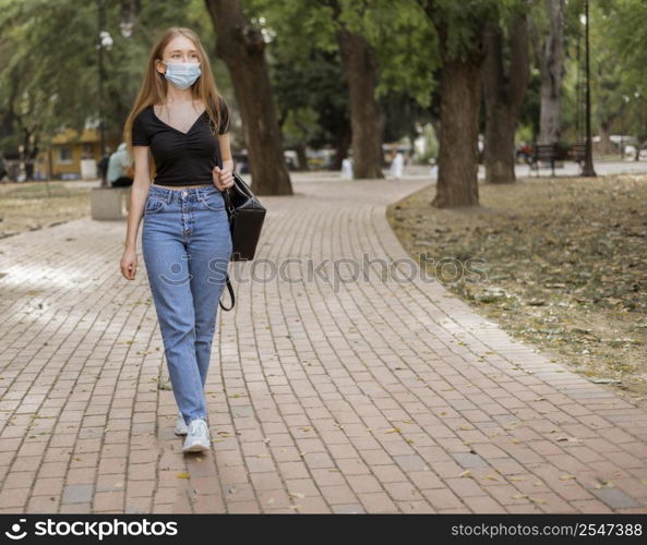 young woman having walk while wearing medical mask