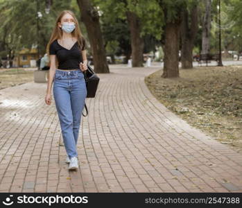 young woman having walk while wearing medical mask