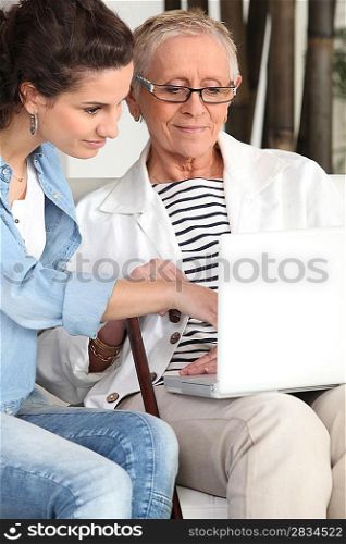 Young woman helping an elderly lady navigate the internet