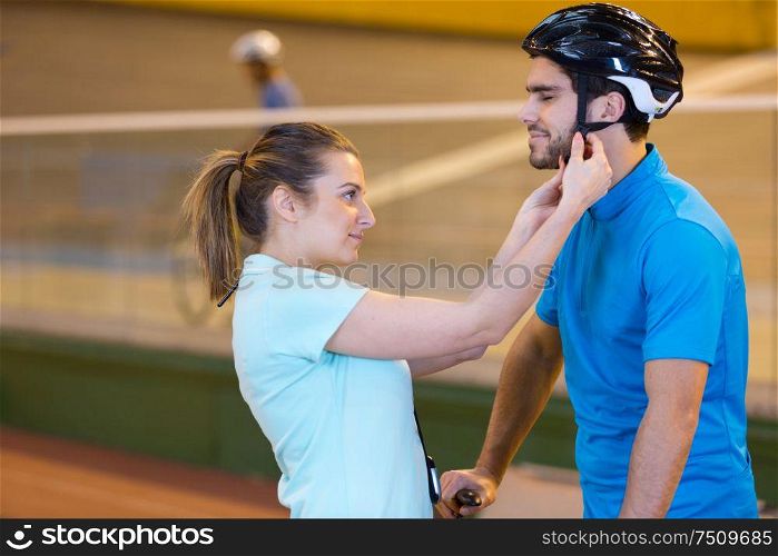 young woman helping her boyfriend to put on bicycle helmet