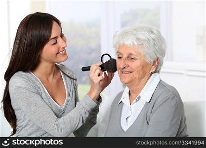 Young woman helping old woman to put makeup on