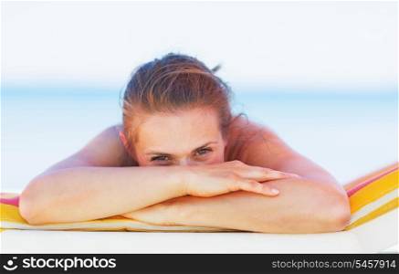 Young woman hide behind hands while laying on chaise-longue
