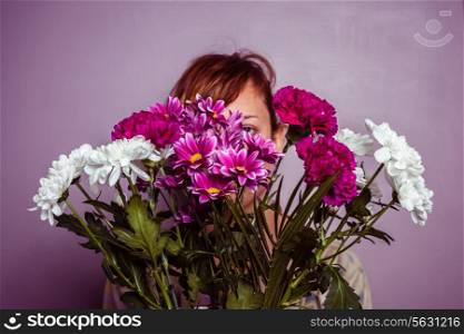 Young woman hiding behind flowers