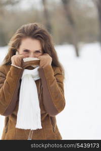 Young woman hiding in winter jacket outdoors