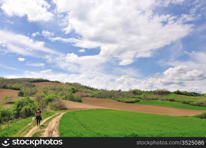Young woman hiker with dog in countryside landscape