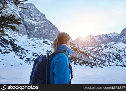 Young woman hiking in snow and watching the sun on mountain top, Austria