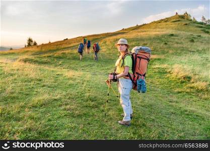 Young woman hiking with friends in the sunset mountains. Young woman hiking with friends