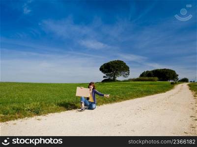Young woman hitch hiking on a beautiful green meadow