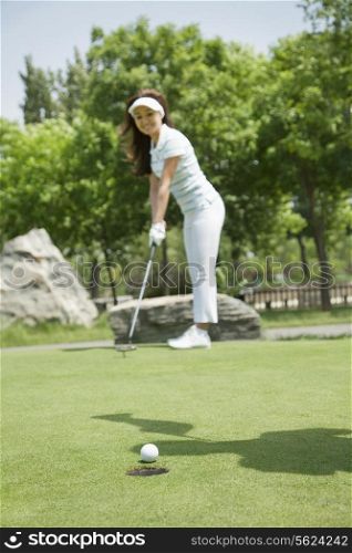 Young woman hitting the ball on the golf course