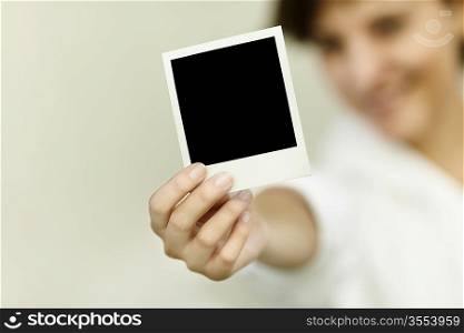 young woman hold blank photo, selective focus on foreground