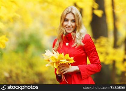 Young woman holding a bunch of autumn leaves