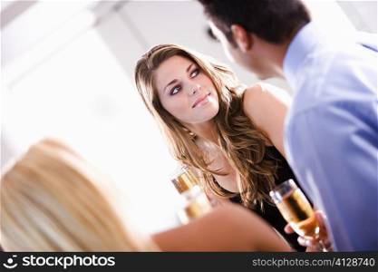 Young woman holding a champagne flute sitting with her friends at a restaurant