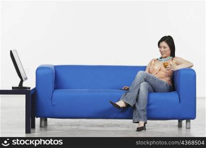Young woman holding a glass of red wine sitting on a couch