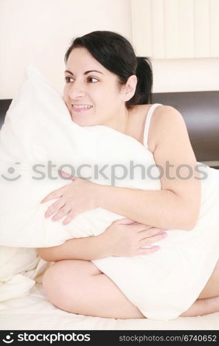 Young woman holding a pillow against a white background