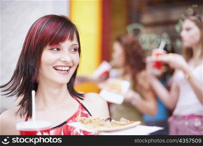 Young woman holding a plate with a cold drink and a slice of pizza