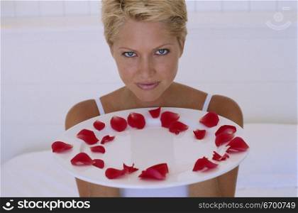 Young woman holding a plate with rose petals
