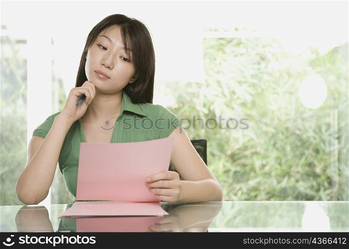 Young woman holding a sheet of paper and thinking