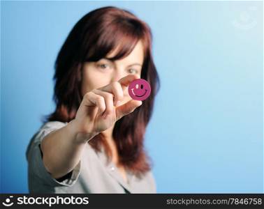Young Woman holding a smiling emoticon. Focus on smile.