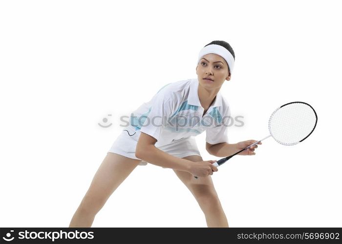 Young woman holding badminton racket while looking away isolated over white background